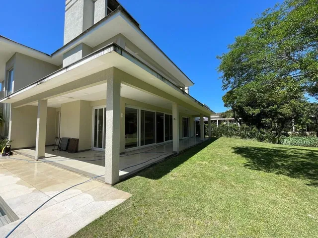 Fachada de uma casa moderna com jardim bem cuidado sob um céu azul.