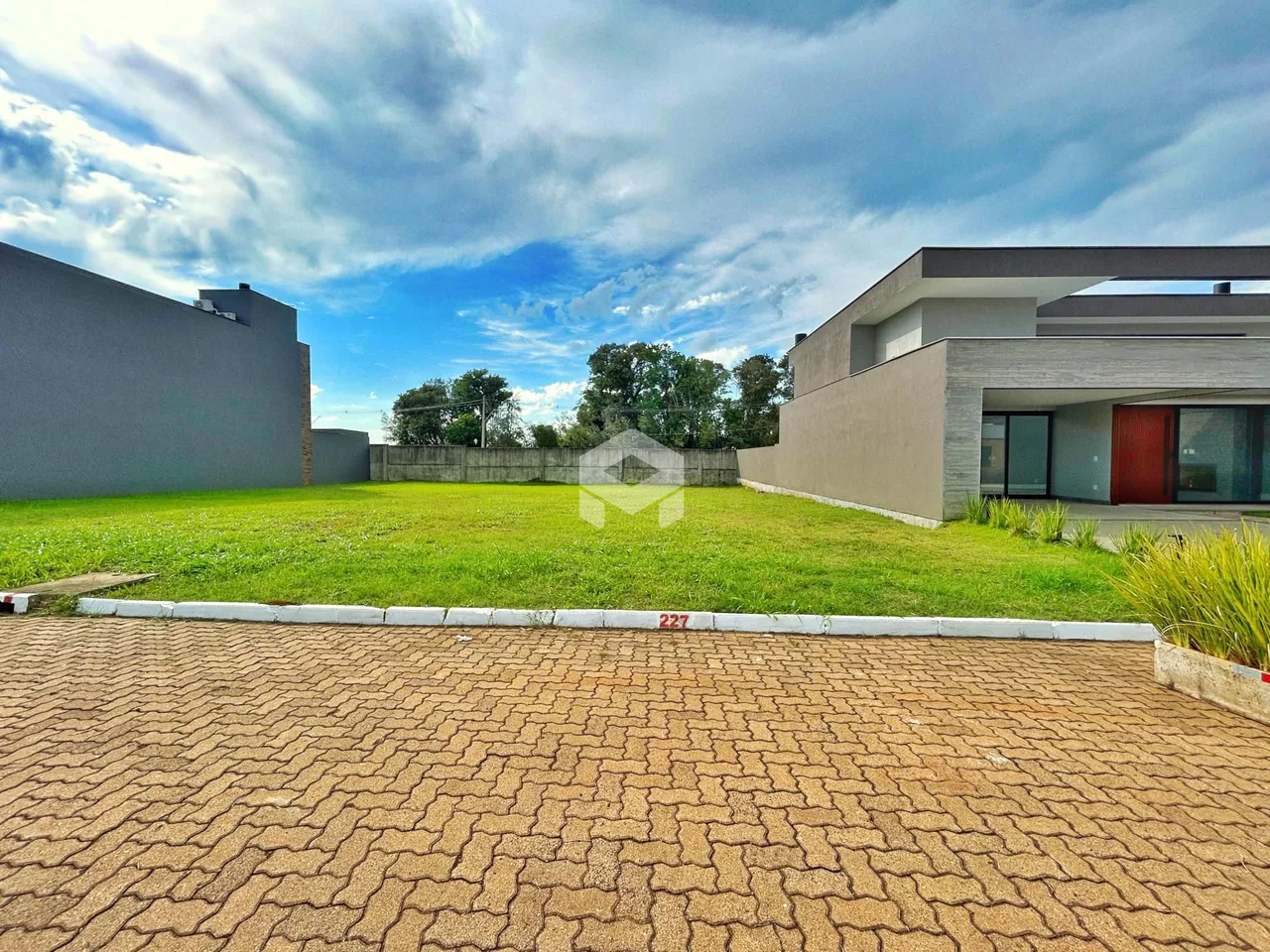 Vista externa de uma propriedade com jardim e área pavimentada.