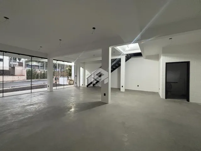 Imagem de um espaço interno amplo com piso de concreto e portas de vidro.
