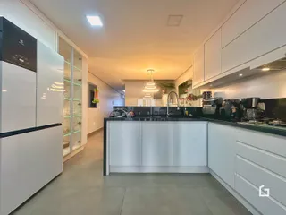 Foto de uma cozinha moderna com armários brancos e bancadas escuras.