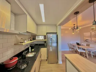 Cozinha moderna com armários brancos, bancadas escuras e eletrodomésticos em aço inoxidável.