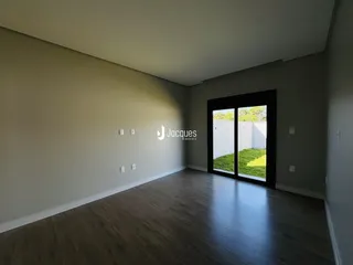 Sala de estar com piso de madeira e porta de vidro que dá para o jardim.