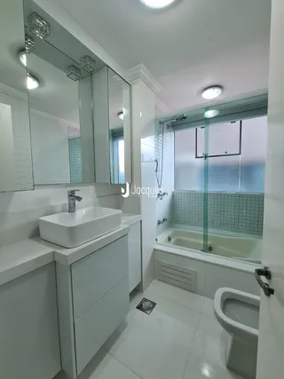 Banheiro moderno com box de vidro e banheira.