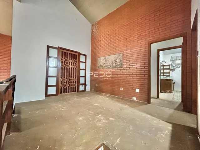 Interior de uma sala com paredes de tijolo aparente e piso de concreto.
