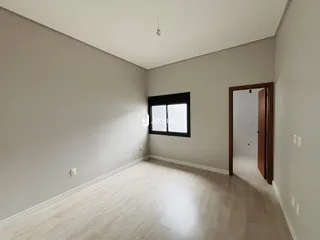 Ambiente interno de uma sala com piso de madeira clara e parede branca.