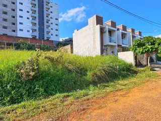 Fachada de um prédio residencial com vegetação alta no primeiro plano.