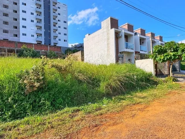 Fachada de um prédio residencial com vegetação alta no primeiro plano.