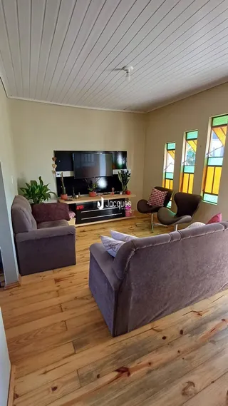 Sala de estar com piso de madeira e móveis de estar.