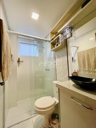 Foto de um banheiro interno com box de vidro e vaso sanitário.