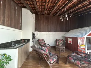 Interior de uma sala com piso de madeira e móveis de vime.