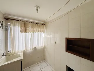 Foto de um banheiro com paredes de azulejo branco e janela com cortinas.