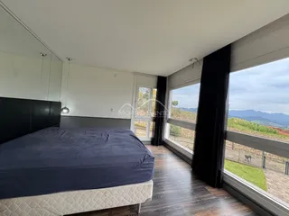 Quarto com cama grande e janela com vista para a paisagem.