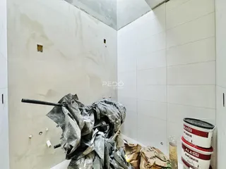 Parede interna com acabamento em concreto aparente e materiais de obra.