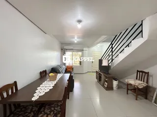 Foto de uma sala de jantar com mesa de madeira e escadaria no fundo.