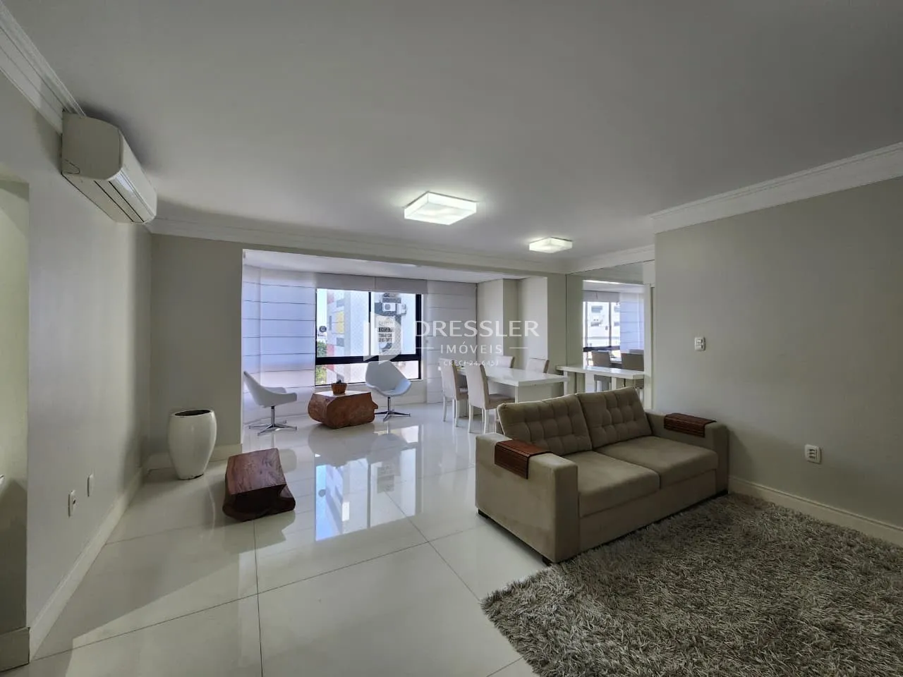 Sala de estar com piso claro e sofá moderno em um imóvel no Brasil.