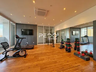 Sala de estar com piso de madeira e equipamentos de ginástica.