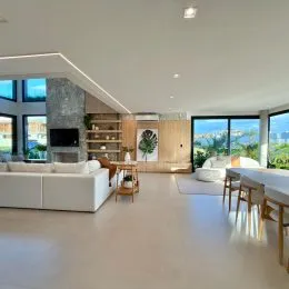 Sala de estar ampla com sofá branco e vista para a paisagem externa.