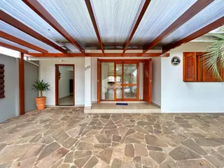 Fachada externa de uma residência em Lajeado, Brasil, com piso de pedra e estrutura de madeira.