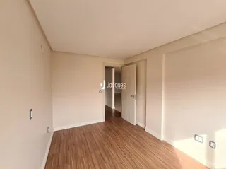 Ambiente interno com piso de madeira e paredes brancas.