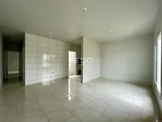 Ambiente interno de uma sala ampla com piso de cerâmica clara.