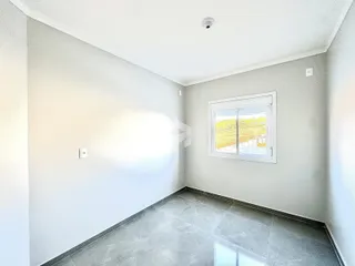 Ambiente interno de uma sala com piso de cerâmica e janela para a paisagem.