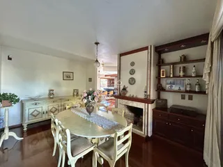 Sala de jantar com piso de madeira e lareira em uma residência.