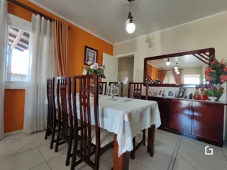 Uma mesa de jantar de madeira com cadeiras é vista no interior da sala.