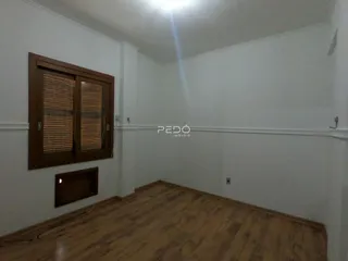 Vista interna de um cômodo com piso de madeira e moldura de janela de madeira.