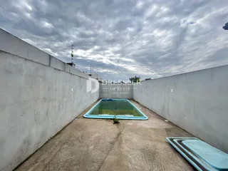 Vista externa de um pátio com uma piscina retangular entre paredes altas.