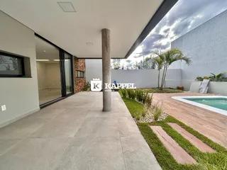 Vista de uma área externa pavimentada com piscina e paisagismo.