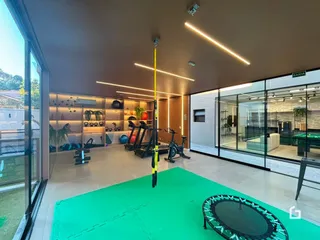 Ambiente interno amplo com equipamentos de ginástica e piso verde.