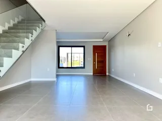 Interior de um espaço amplo com piso de grande formato e escadaria de vidro.