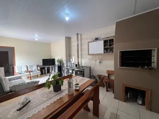 Sala de estar e jantar com mesa de madeira e sofá no interior de uma residência.