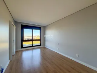 A sala de estar possui piso de madeira clara e uma grande janela com vista para o exterior.