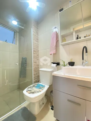 Interior de um banheiro com azulejos brancos e box de vidro.