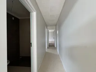 Corredor interno com paredes brancas e piso claro, mostrando a profundidade do ambiente.