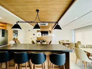 Ambiente de jantar com mesa escura e iluminação pendente moderna.