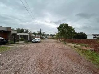 Vista da entrada de uma propriedade com estrada de cascalho e vegetação ao fundo.
