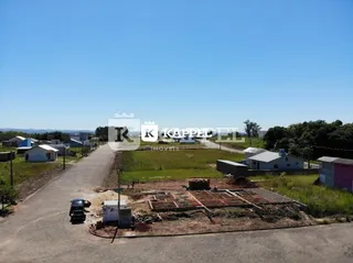 Vista externa de um terreno vazio com acesso por estrada de terra.