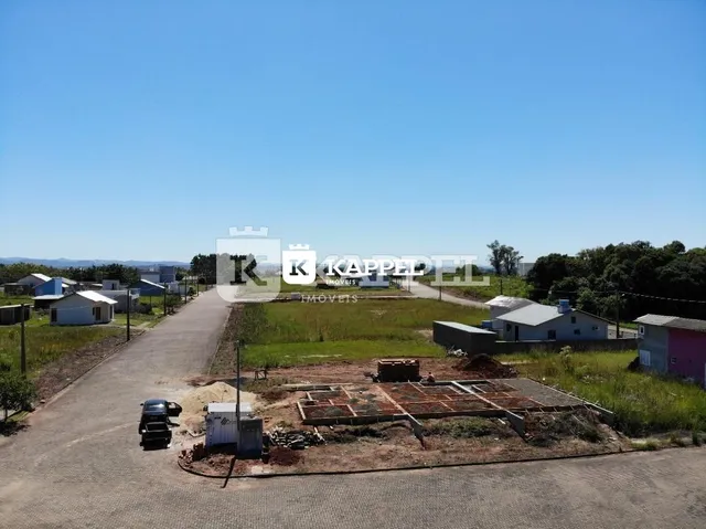 Vista externa de um terreno vazio com acesso por estrada de terra.