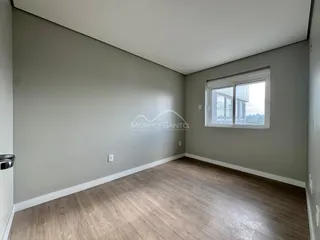 Ambiente interno com paredes cinzas e piso de madeira clara.