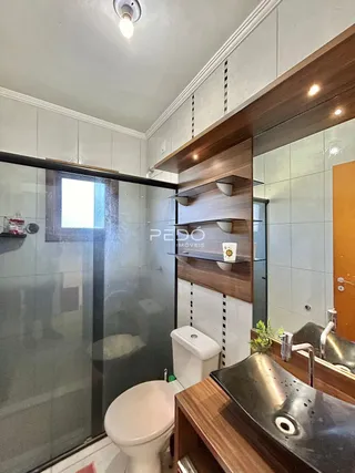 Foto de um banheiro com box de vidro e louças sanitárias.
