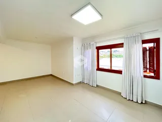 Ambiente interno de uma sala ampla com piso de cerâmica e janela.