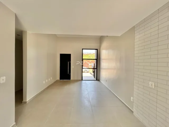 A foto mostra um corredor interno com paredes brancas e piso claro.
