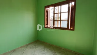 Uma parede verde com uma janela de madeira é visível no interior da sala.