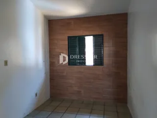 A foto mostra um corredor interno com paredes brancas e revestimento de madeira.