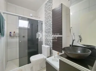 Foto de um banheiro interno com box de vidro e louças sanitárias.