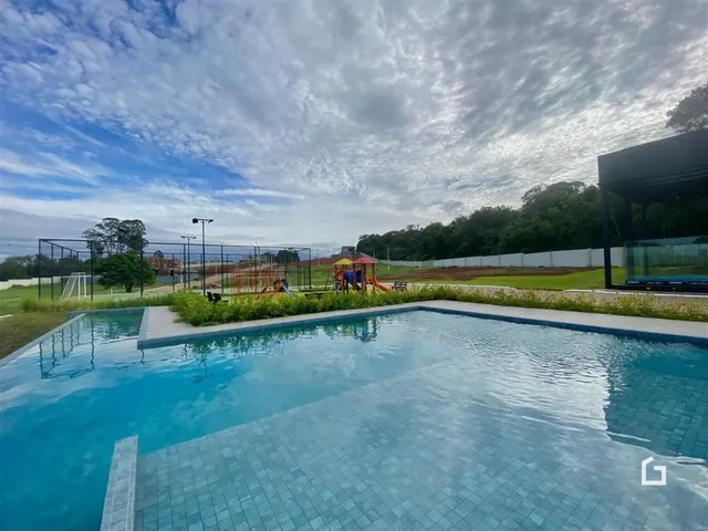 Foto de uma piscina externa e área verde com campo de esportes.