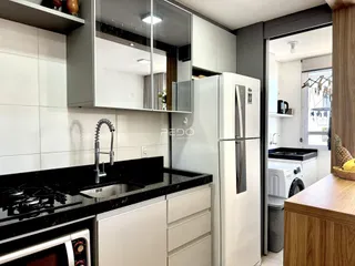 Cozinha moderna com armários brancos e bancada preta.