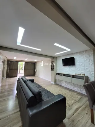 Uma sala de estar ampla com piso de madeira e sofá de couro.